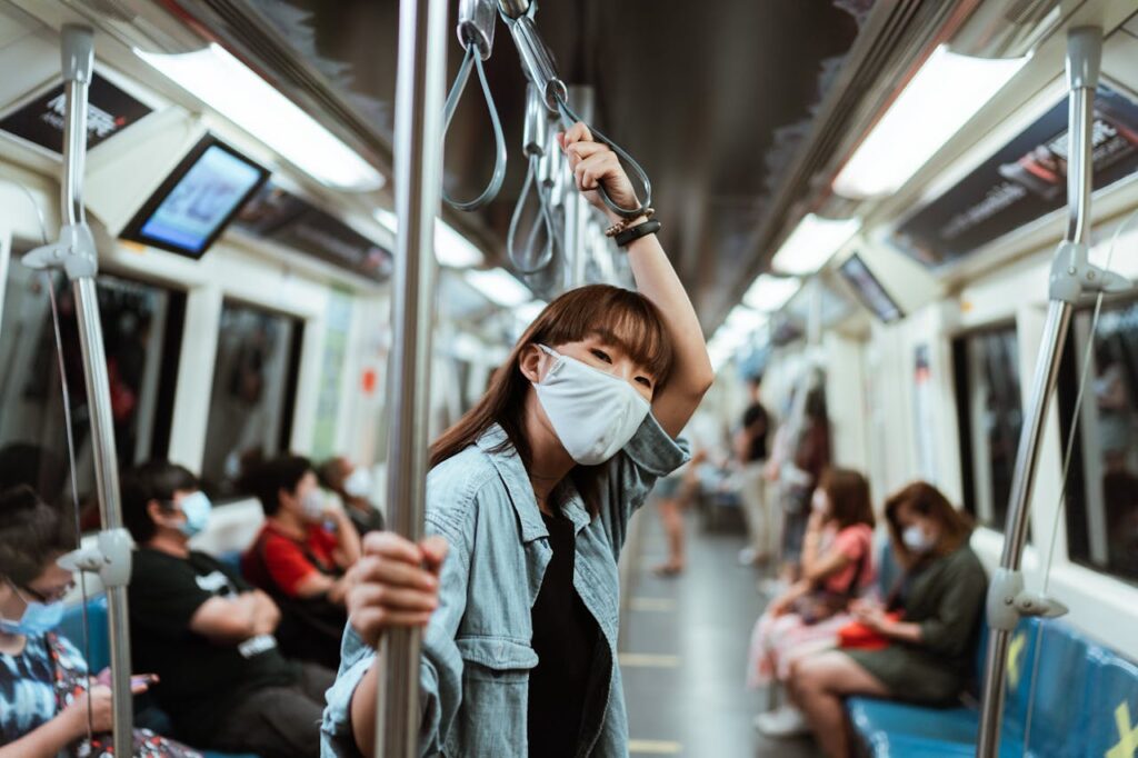 Asian woman wearing a face mask on a subway train during the pandemic, showcasing modern transportation.