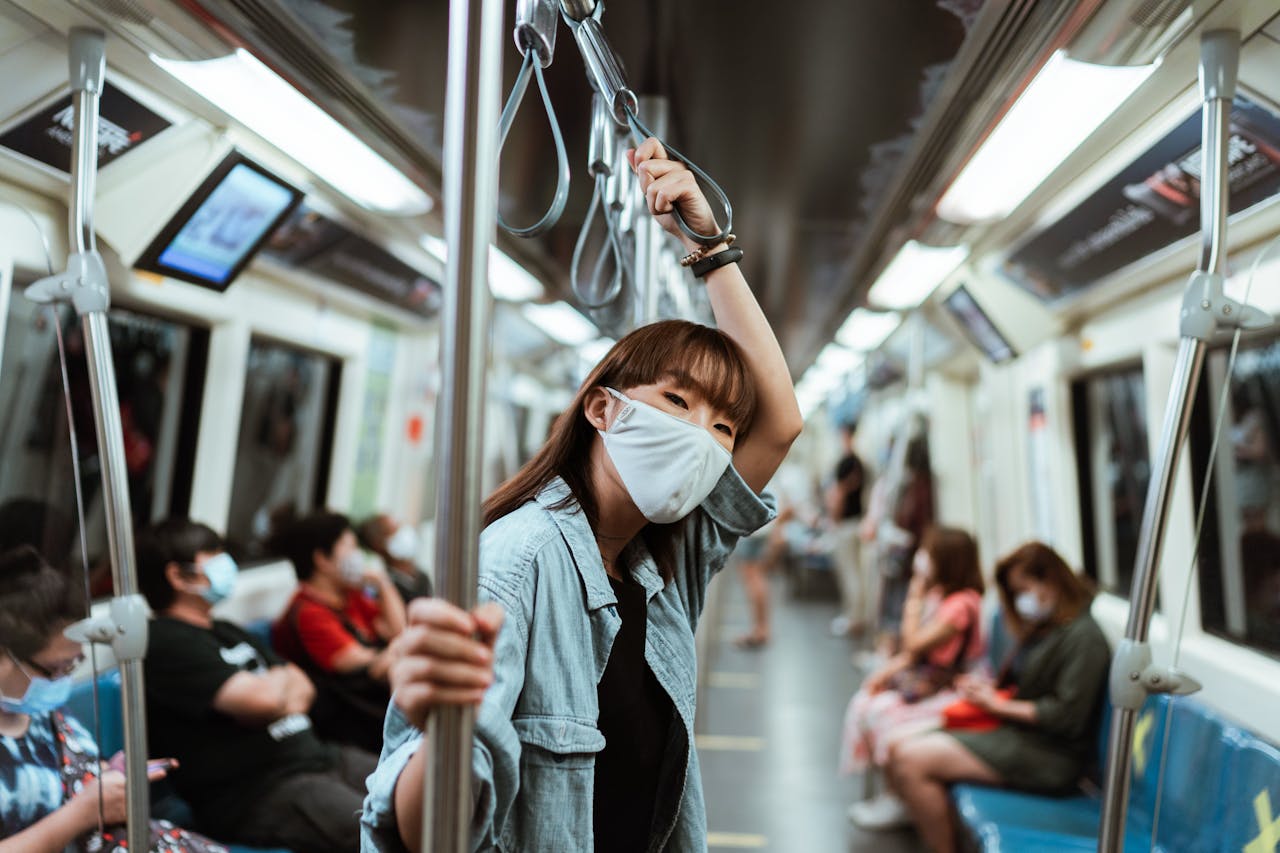 Asian woman wearing a face mask on a subway train during the pandemic, showcasing modern transportation.